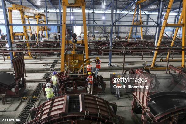 Workers pour concrete from a kibble into the mold of a precast concrete tunnel segment at the Mumbai Metro Rail Corp. Casting yard in Mumbai, India,...