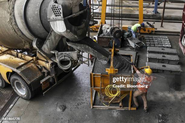 Worker guides concrete from a mixer truck into a kibble at the Mumbai Metro Rail Corp. Casting yard in Mumbai, India, on Monday, Aug. 28, 2017. The...