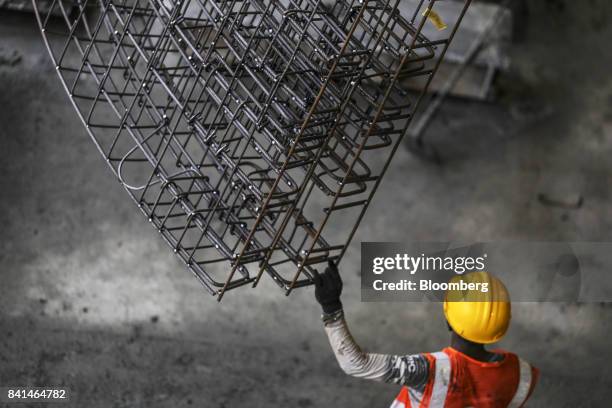 Worker guides the steel reinforcing frame of a precast concrete tunnel segment being maneuvered by crane to a mold at the Mumbai Metro Rail Corp....