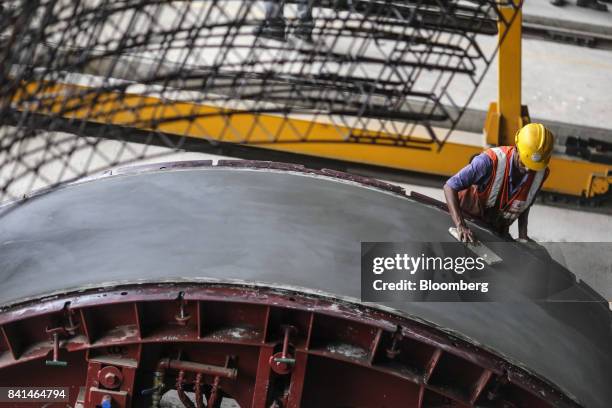 Worker smooths the surface of a precast concrete tunnel segment as it sits in a mold at the Mumbai Metro Rail Corp. Casting yard in Mumbai, India, on...