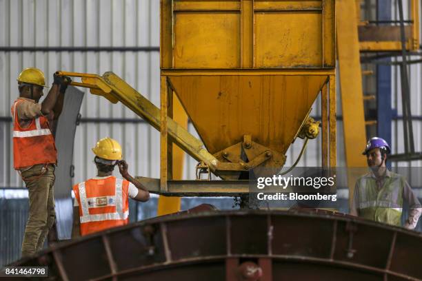 Workers pour concrete from a kibble into a mold of precast concrete tunnel segment at the Mumbai Metro Rail Corp. Casting yard in Mumbai, India, on...