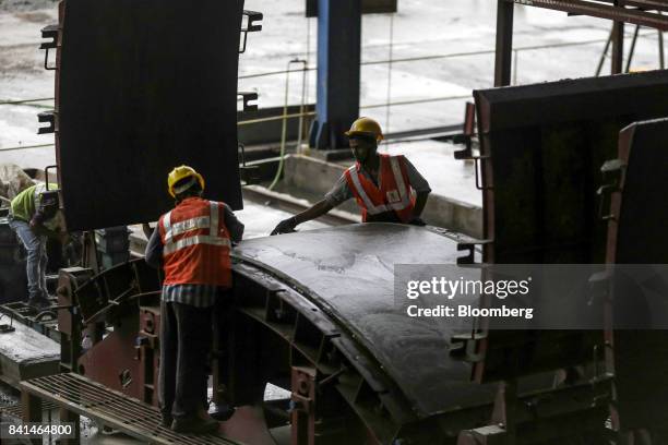 Workers smooth the surface of a precast concrete tunnel segment as it sits in a mold at the Mumbai Metro Rail Corp. Casting yard in Mumbai, India, on...