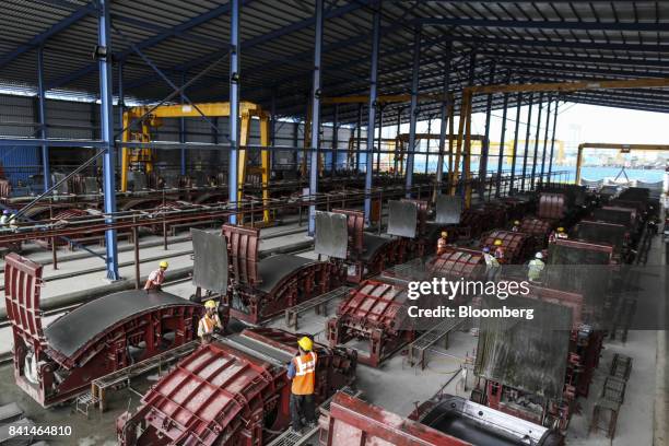 Workers open the molds of precast concrete tunnel segment at the Mumbai Metro Rail Corp. Casting yard in Mumbai, India, on Monday, Aug. 28, 2017. The...