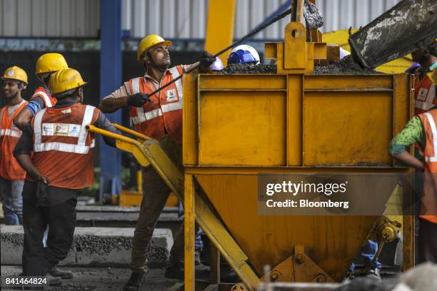 Workers guide concrete from a mixer truck into a kibble at the Mumbai Metro Rail Corp. Casting yard in Mumbai, India, on Monday, Aug. 28, 2017. The...