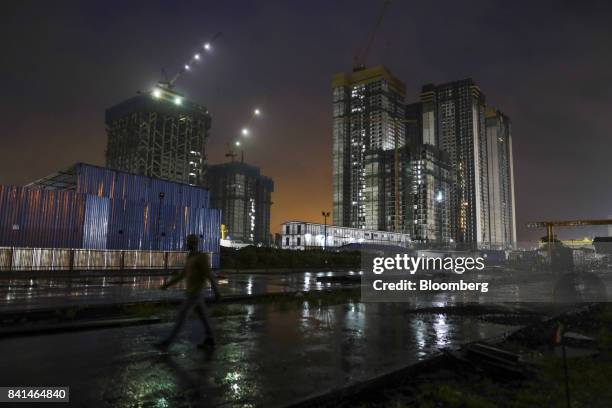 Worker walks through the Mumbai Metro Rail Corp. Casting yard as buildings under construction stand illuminated at night in Mumbai, India, on Monday,...