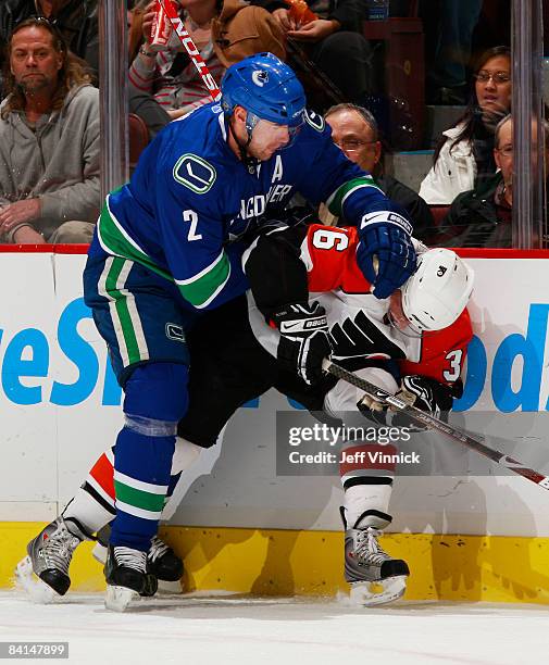 Mattias Ohlund of the Vancouver Canucks hits Darroll Powe of the Philadelphia Flyers hard along the boards during their game at General Motors Place...