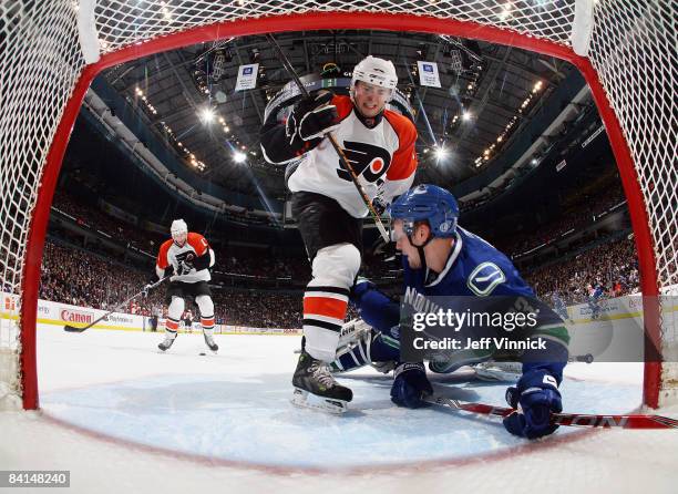 Joffrey Lupul of the Philadelphia Flyers checks Alexander Edler of the Vancouver Canucks to the ice during their game at General Motors Place on...