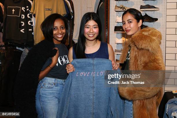 Bethie Girmai and Petta Chua pose for a photo with a Universal Store employee during Vogue American Express Fashion's Night Out 2017 on September 1,...