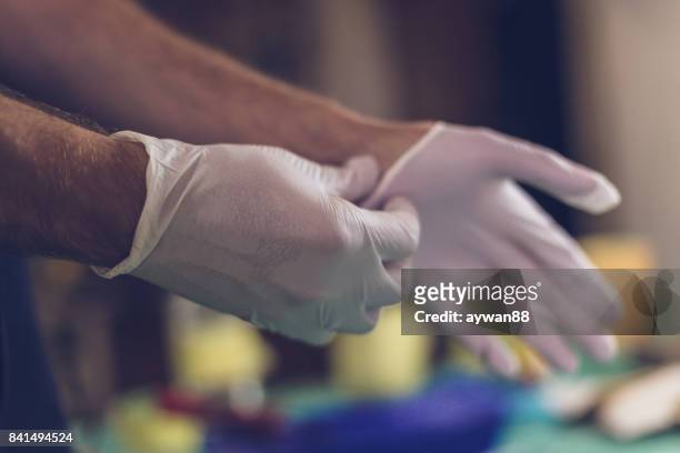 male hands putting on latex gloves - surgical glove stock pictures, royalty-free photos & images