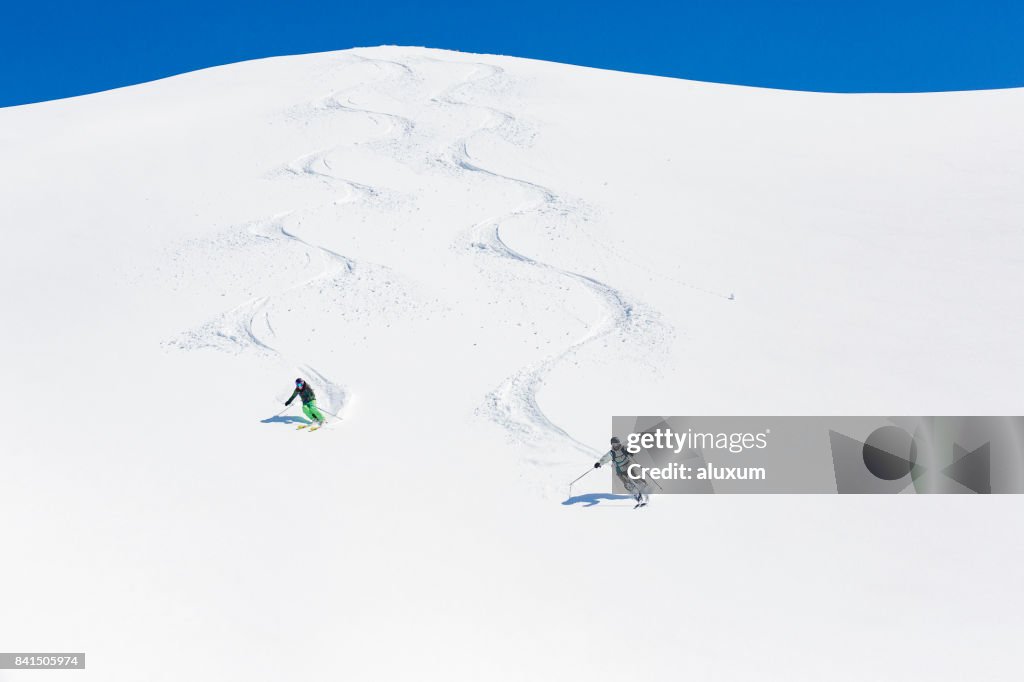 Man and woman skiing down mountain