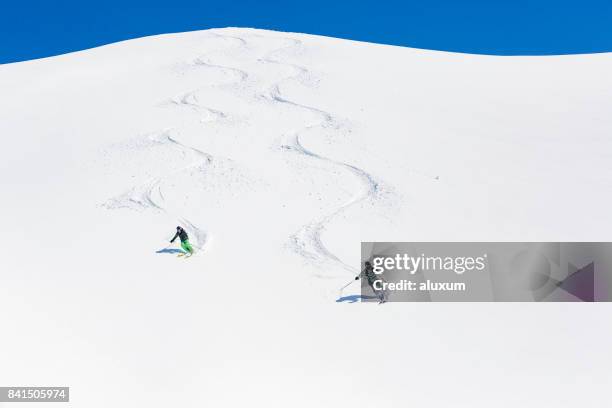 man and woman skiing down mountain - baqueira beret stock pictures, royalty-free photos & images