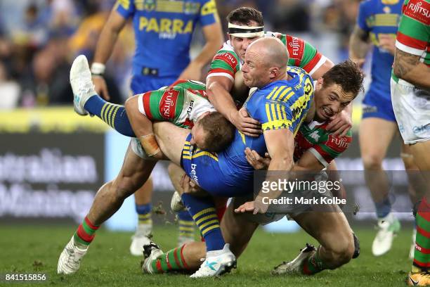 Beau Scott of the Eels is tackled by Jason Clark and Dave Tyrrell of the Rabbitohs during the round 26 NRL match between the Parramatta Eels and the...