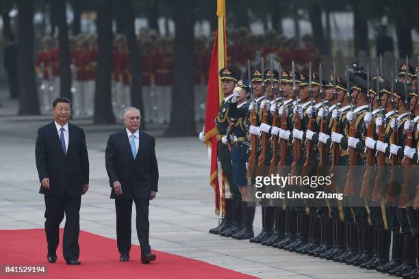 Chinese President Xi Jinping accompanies Brazilian President Michel Temer to view a guard of honour during a welcoming ceremony outside the Great...