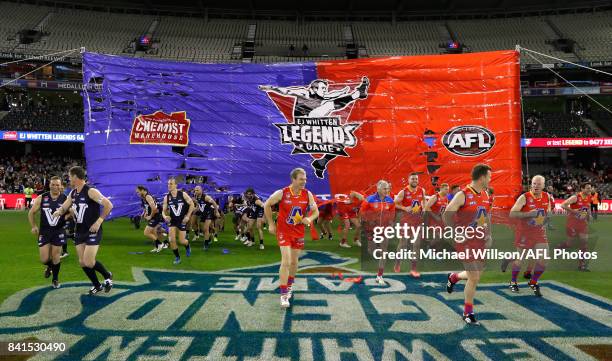 Players run through the banner during the 2017 EJ Whitten Legends Game between Victoria and the All Stars at Etihad Stadium on September 1, 2017 in...