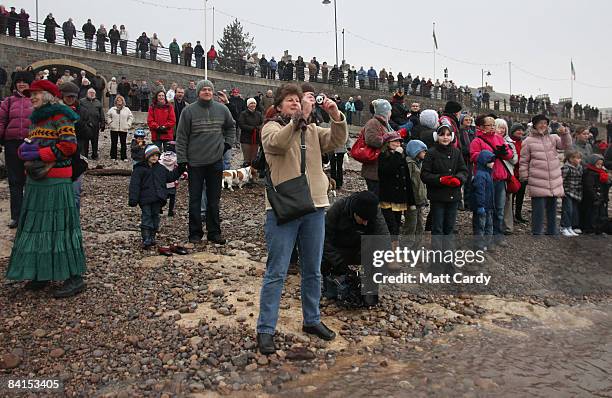 People watch as members of the Middle Yeo Surf Lifesaving Club take part in their annual charity New Years Day swim in the Bristol Channel on January...