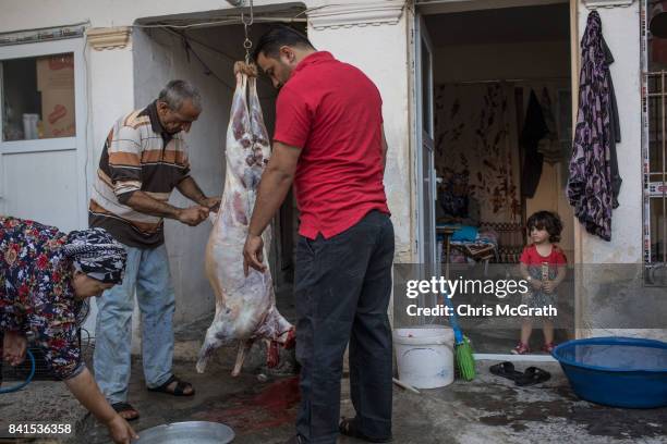 Syrian refugee Husin Lok helps family members cut the meat off a sacrificial sheep at their home during Eid-al-Adha celebrations on September 01,...