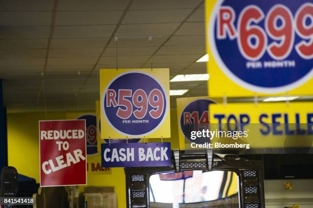 Advertisements for price reductions and monthly rand cash back schemes hang from the ceiling of a Russells furniture and electronics store, operated...