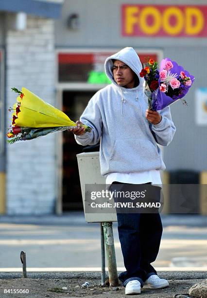 Man waits for customers to sell flowers at an intersection in Glendale, California, on January 1, 2009. New US jobless claims fell by 94,000 in the...