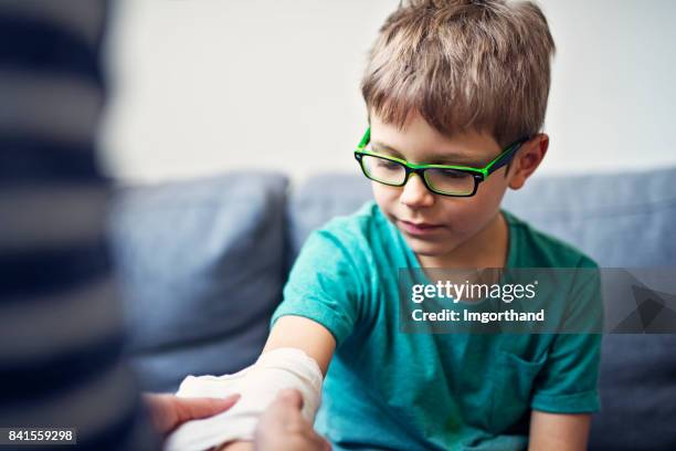 mother tending to her son's wounded arm - elbow bandage stock pictures, royalty-free photos & images