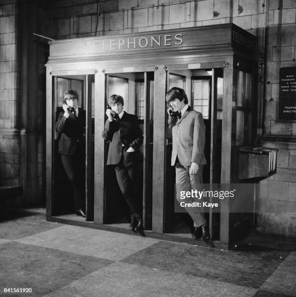 Singer John Lennon , drummer Ringo Starr, and guitarist George Harrison in telephone kiosks at Marylebone Station while filming musical comedy film...