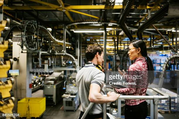 mechanic and female engineer talking in factory - manufacturing stock pictures, royalty-free photos & images