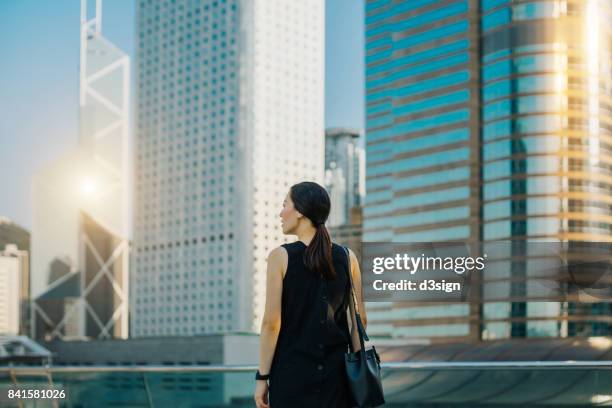 young woman looking towards the busy and energetic city skyline of hong kong - central asia stock-fotos und bilder