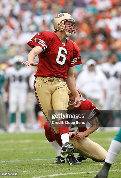 Place kicker Joe Nedney of the San Francisco 49ers follows through on a field goal attempt out from under the hold of holder Andy Lee while taking on...