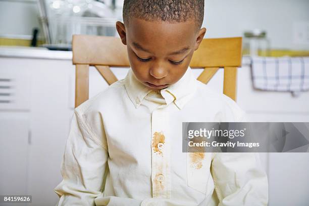 young boy looking at shirt's food stains - stained shirt stock pictures, royalty-free photos & images