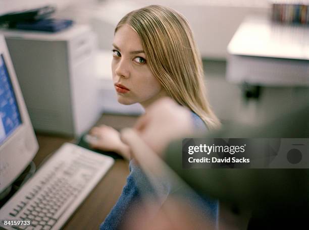 woman at desk giving dirty look to prankster. - furious stock-fotos und bilder