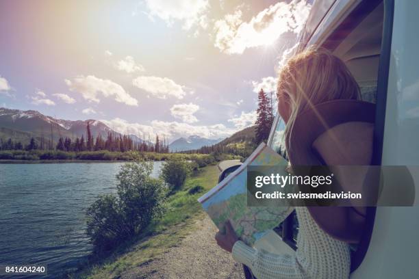 jonge vrouw kijkt routekaart in de buurt van bergmeer - canadian map stockfoto's en -beelden