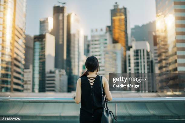 Rear view of woman looking out over urban cityscape against sky