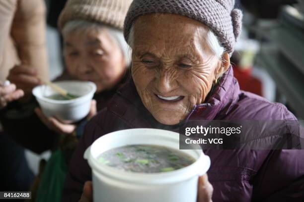 Grandmother eats the free laba porridge given out by Guangxiao temple on January 9,2009 in Taizhou, east China's Jiangsu province. From Qin Dynasty ,...
