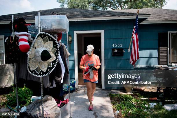 Woman walks out of her home with personal items salvaged from a once flooded house as residents begin the recovery process from Hurricane Harvey on...