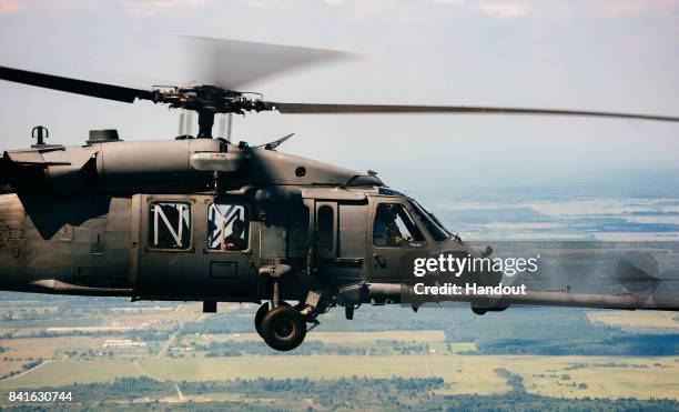 In this U.S. Air Force handout, An HH-60 Pavehawk from the 106th Rescue Squadron, approaches a C-130 Hercules to refuel over Texas on the way to aide...