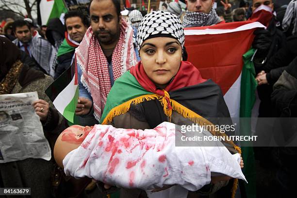 Protesters opposed to Israeli military action in the Gaza Strip carries a doll with fake blood stains on it during a demonstration in Amsterdam, on...