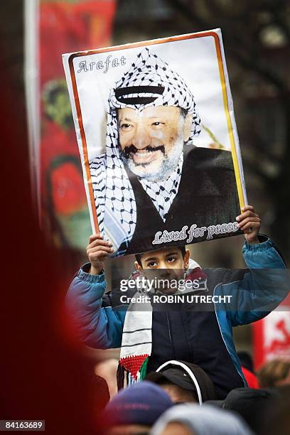 Young protester opposed to Israeli military action in the Gaza Strip carries a portrait of Yasser Arafat during a demonstration in Amsterdam, on...