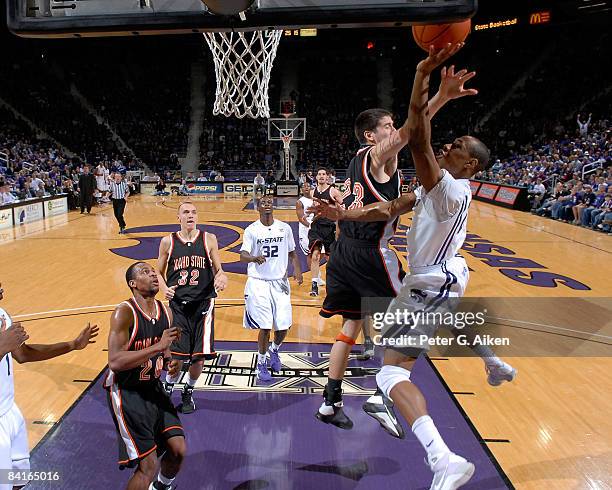 Forward Dominique Sutton of the Kansas State Wildcats drives to the basket against pressure from guard Austin Kilpatrick of the Idaho State Bengals...