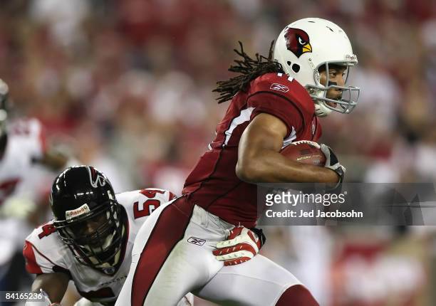 Wide receiver Larry Fitzgerald of the Arizona Cardinals runs with the ball after a reception past Stephen Nicholas of the Atlanta Falcons during the...