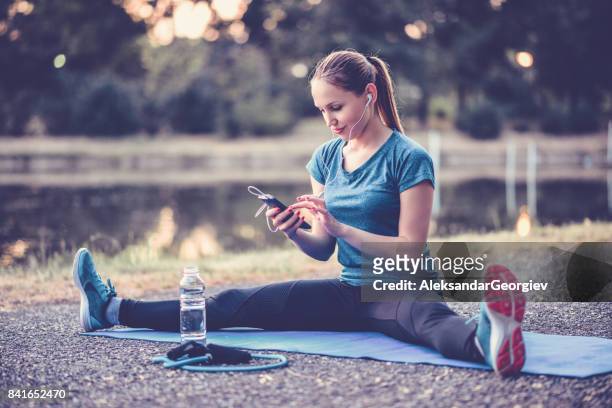 junge sportler weiblich vorbereitung playlist für outdoor-aerobic pilates training - spagat stock-fotos und bilder
