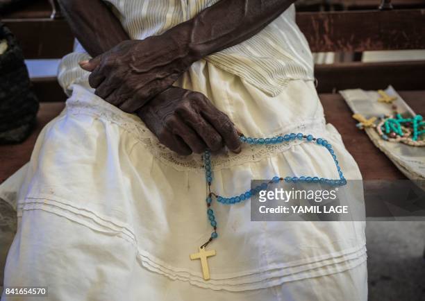 Catholic faithful holds a beaded rosary as she prays at Jovellanos' Church, Matanzas province, Cuba on August 9, 2017. / AFP PHOTO / YAMIL LAGE