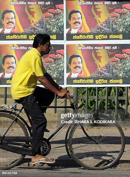 Sri Lankan cyclist rides past a poster on a street in Colombo on January 4 featuring an image of Sri Lankan President Mahinda Rajapakse and hailing...