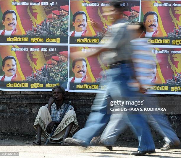 An elderly Sri Lankan man sits under posters on a street in Colombo on January 4 featuring an image of Sri Lankan President Mahinda Rajapakse and...
