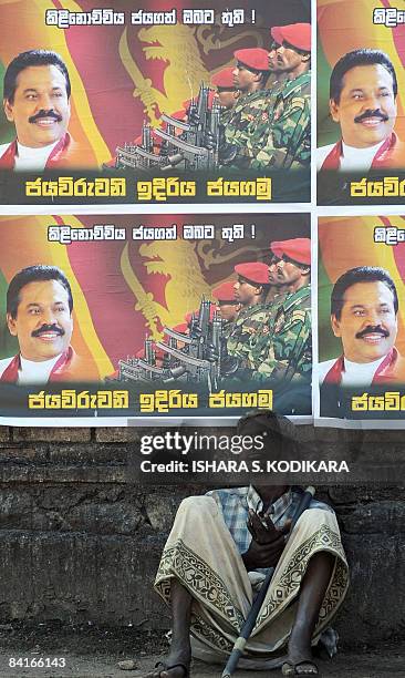 An elderly Sri Lankan man sits under posters on a street in Colombo on January 4 featuring an image of Sri Lankan President Mahinda Rajapakse and...
