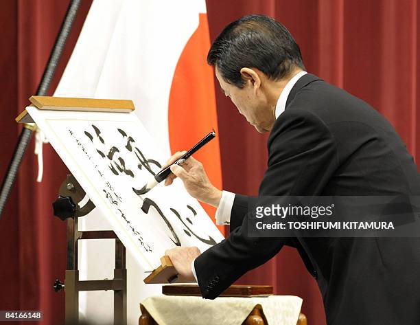 Japanese Prime Minister Taro Aso shows writes a calligraphy "Anshin" and "Katsuryoku" during a press conference in Tokyo on January 4, 2009. Aso...