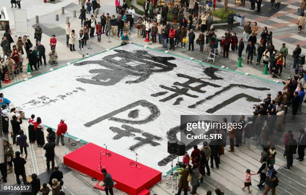 Japanese calligraphers write large Chinese characters "new", "open" and "dream" using a brush, 1.8-meter in length and weighing 20kg, on a large silk...