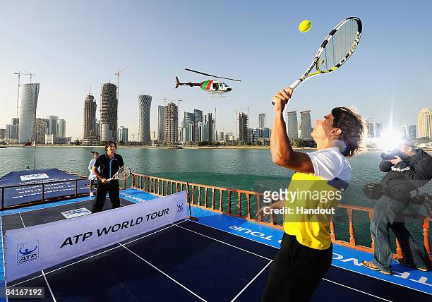 Rafael Nadal of Spain and Roger Federer of Switzerland play tennis on top of a Dhow in Doha Bay to launch the 2009 ATP World Tour during previews for...