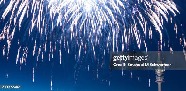 spectacular, majestic fireworks display with colorful starburst explosives exploding in the night sky, rockets shot up bursting, glowing, sparkling and streaking lights during summer festival with munich’s . tv tower in background illuminated - exploding tv stock pictures, royalty-free photos & images