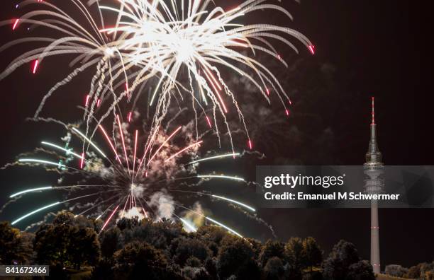 spectacular, majestic fireworks display with colorful starburst explosives exploding in the night sky, rockets shot up bursting, glowing, sparkling and streaking lights during summer festival with munich’s . tv tower in background illuminated - olympiapark stock pictures, royalty-free photos & images