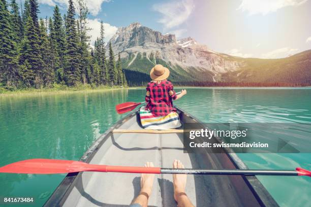 pov of couple paddling red canoe on turquoise lake - kayaker woman stock pictures, royalty-free photos & images