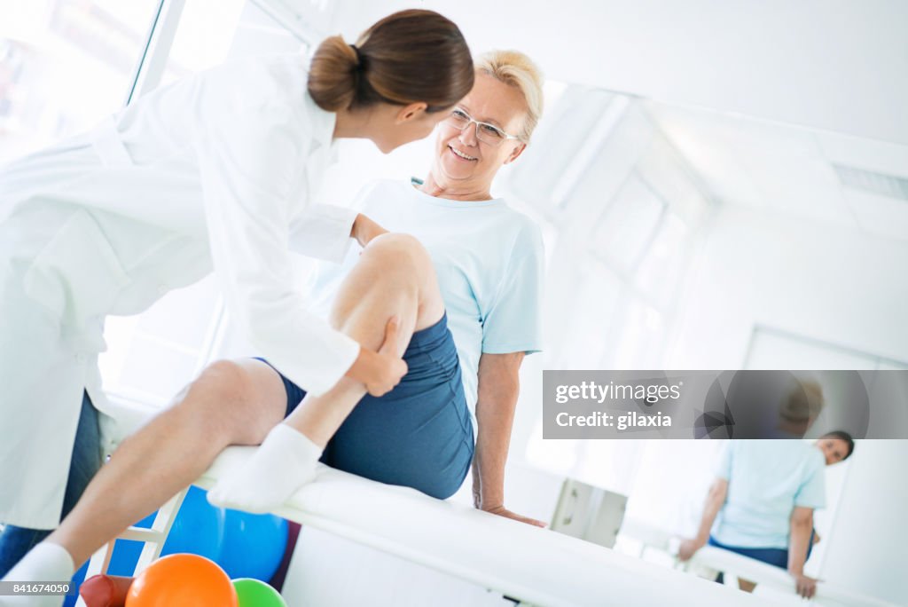 Senior vrouw na onderzoek van de knie.